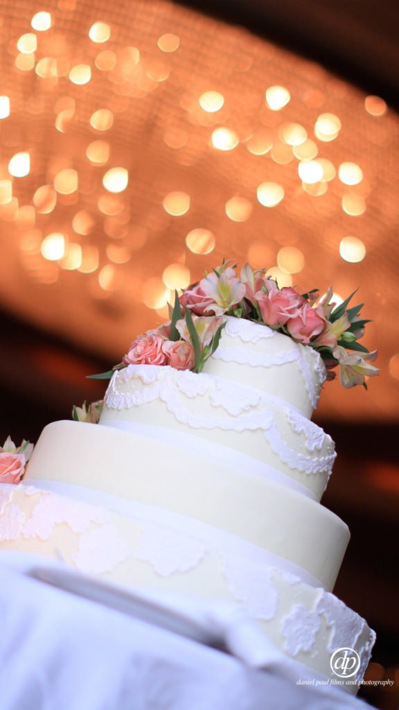 Photo of a wedding cake in the foreground and out of focus lighting in the background.