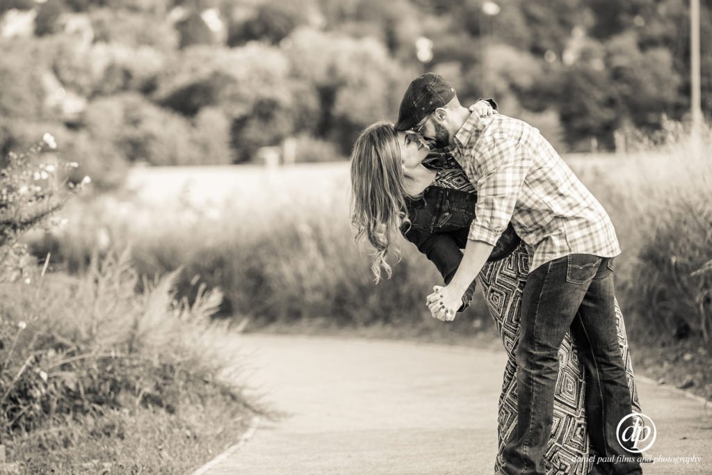 Black and white photo of a couple kissing, the man dipping the woman back as if they were dancing.