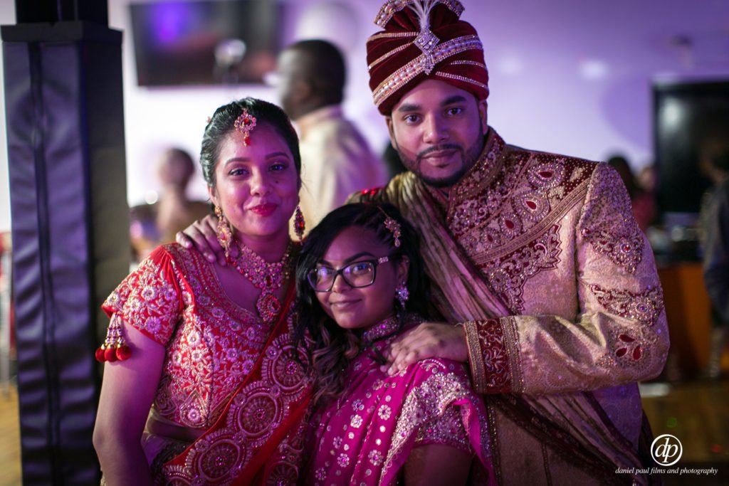 A man, woman and child in traditional Indian clothes celebrating at a wedding.